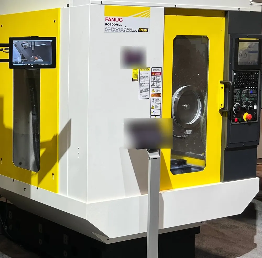 FANUC ROBODRILL at a trade show with a Rotoclear camera image on a monitor beside the door and a Rotoclear S3 in the door window