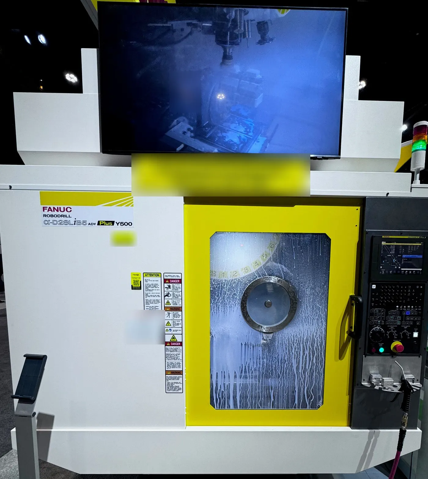 FANUC ROBODRILL at a trade show with a Rotoclear S3 spinning window in the door and a Rotoclear camera image of the work area on the monitor above